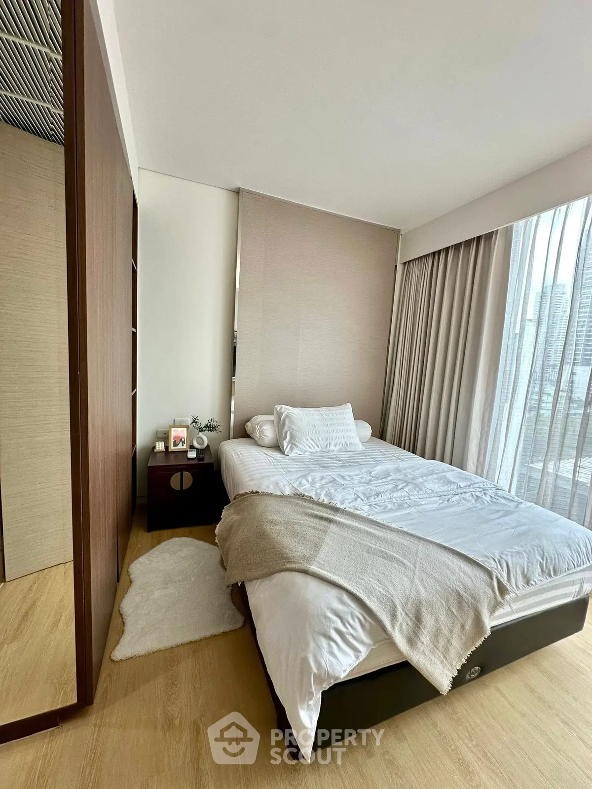Cozy modern bedroom with city view, featuring a comfortable bed and elegant decor.
