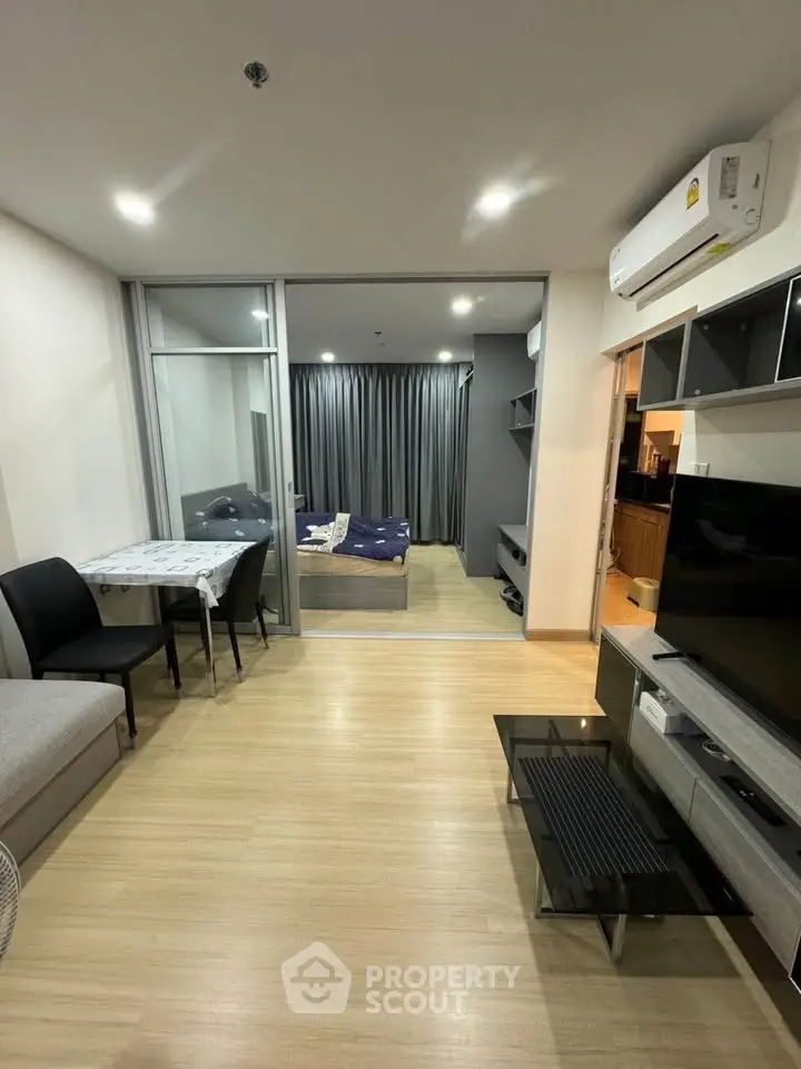 Modern open-plan living room with cozy bedroom and sleek kitchen in a stylish apartment.