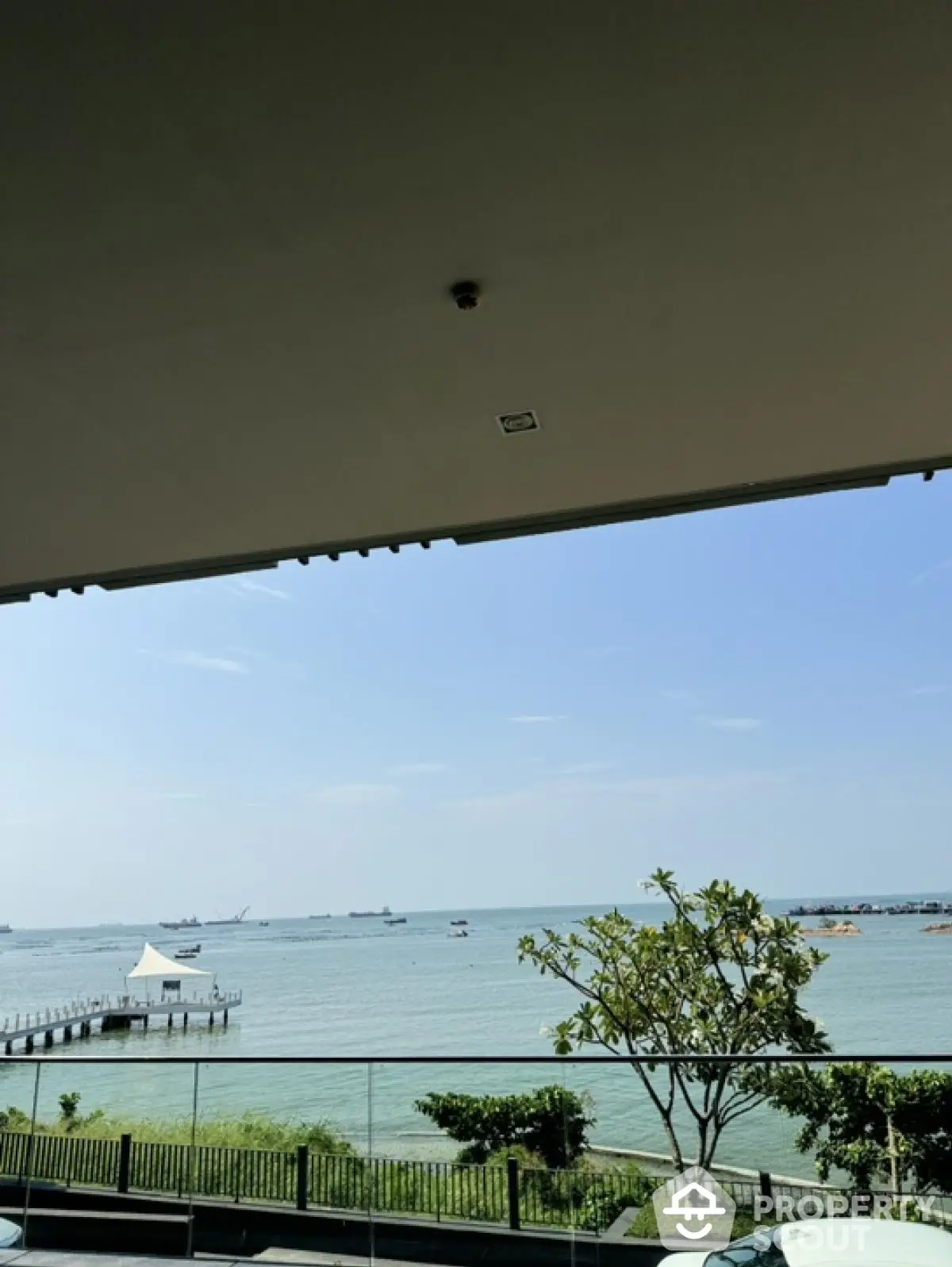 Stunning waterfront view from a modern balcony with lush greenery and serene ocean scenery.