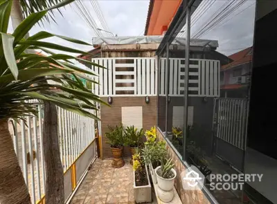 Charming exterior view with potted plants and modern fencing in a cozy residential setting.