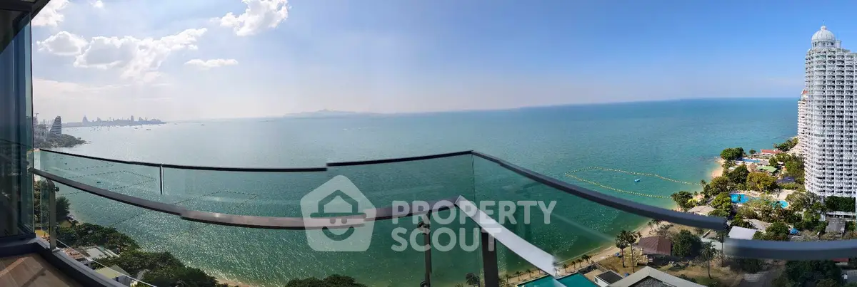 Stunning panoramic ocean view from a high-rise balcony with clear blue skies.