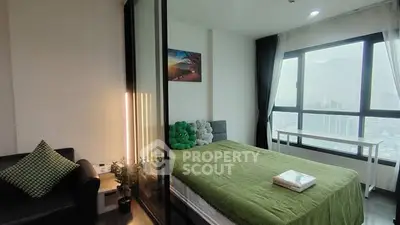 Modern bedroom with city view, green bedding, and cozy decor in a high-rise apartment.