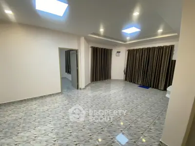 Spacious modern living room with elegant tile flooring and large windows.