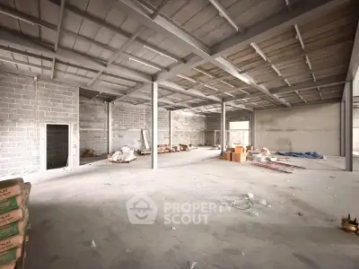 Spacious industrial warehouse interior with high ceilings and concrete flooring.