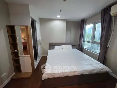 Spacious bedroom with large windows and modern decor in a city apartment.