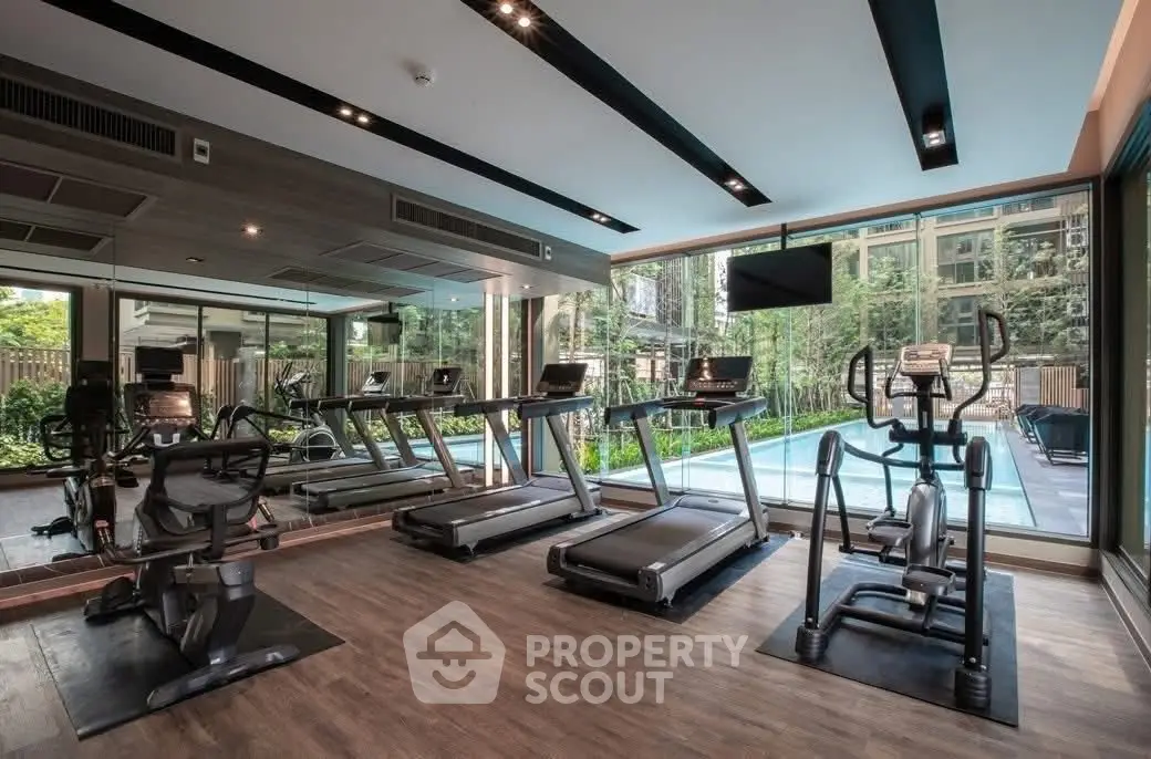 Luxurious gym with modern equipment and pool view in upscale residential building.