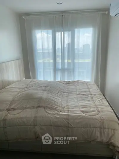Cozy bedroom with large window and soft natural light, perfect for relaxation.