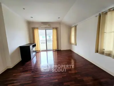 Spacious living room with hardwood floors and large windows offering natural light and balcony access.