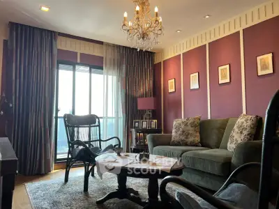 Elegant living room with chandelier, plush sofa, and large window offering natural light.