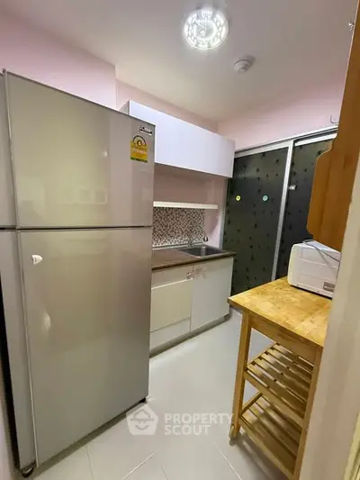 Compact kitchen with modern fridge and microwave, featuring a sleek design and efficient layout.