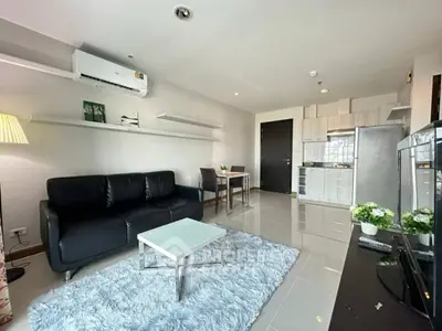 Modern living room with sleek black sofa, stylish kitchen, and cozy dining area in open layout apartment.