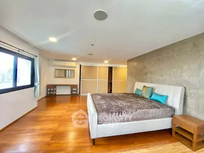 Spacious modern bedroom with wooden flooring and large windows