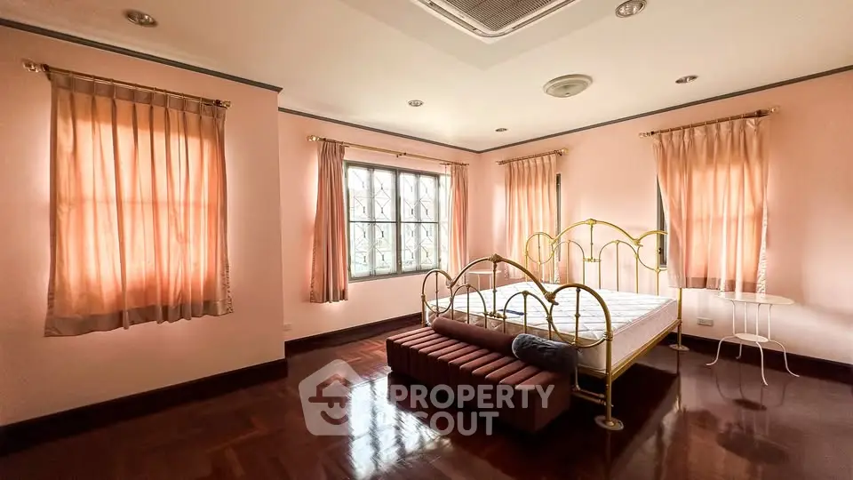 Spacious bedroom with elegant brass bed and natural light, perfect for relaxation.