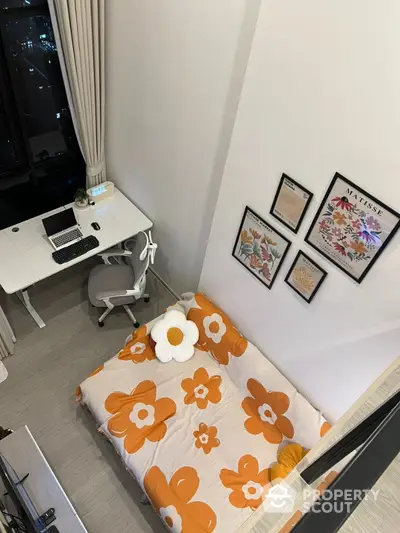 Modern bedroom with stylish decor and workspace, featuring floral bedding and framed art on the wall.