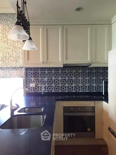 Charming kitchen with elegant cabinetry and modern appliances, featuring a stylish backsplash and dual sinks.