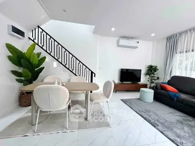 Modern living room with stylish dining area and staircase, featuring elegant decor and natural light.