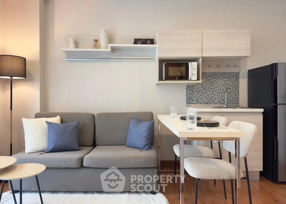 Modern living room with compact kitchen, stylish sofa, and dining area in a cozy apartment.