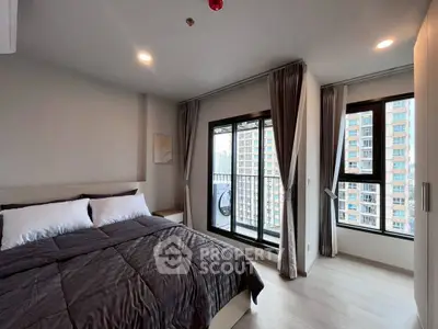 Modern bedroom with large windows and city view, featuring a cozy bed and stylish decor.