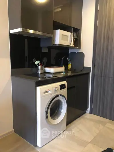 Modern kitchen with sleek cabinetry, built-in microwave, and washing machine in compact layout.