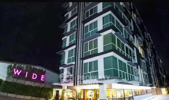 Modern high-rise building with illuminated facade at night, showcasing urban living.