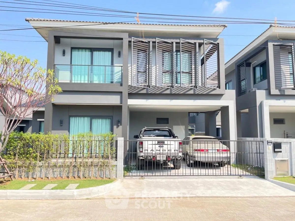 Modern two-story house with balcony and garage in a suburban neighborhood.