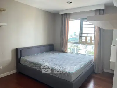 Spacious bedroom with city view and modern decor in high-rise apartment.