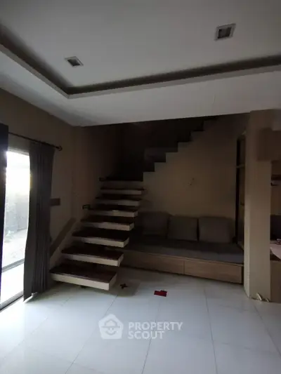 Modern interior with floating staircase and cozy seating area, perfect for stylish living.