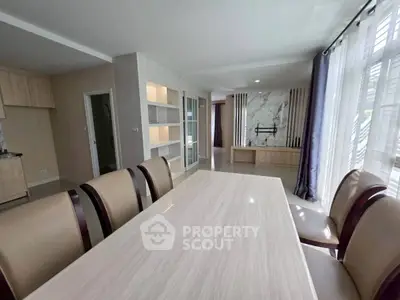 Spacious dining area with elegant table and chairs, open layout to modern living room.