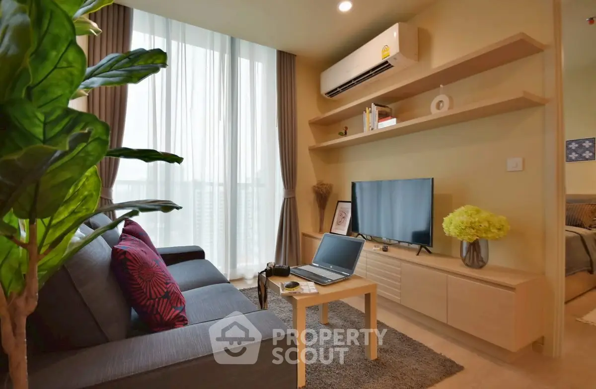 Modern living room with cozy sofa, TV, and large window for natural light.