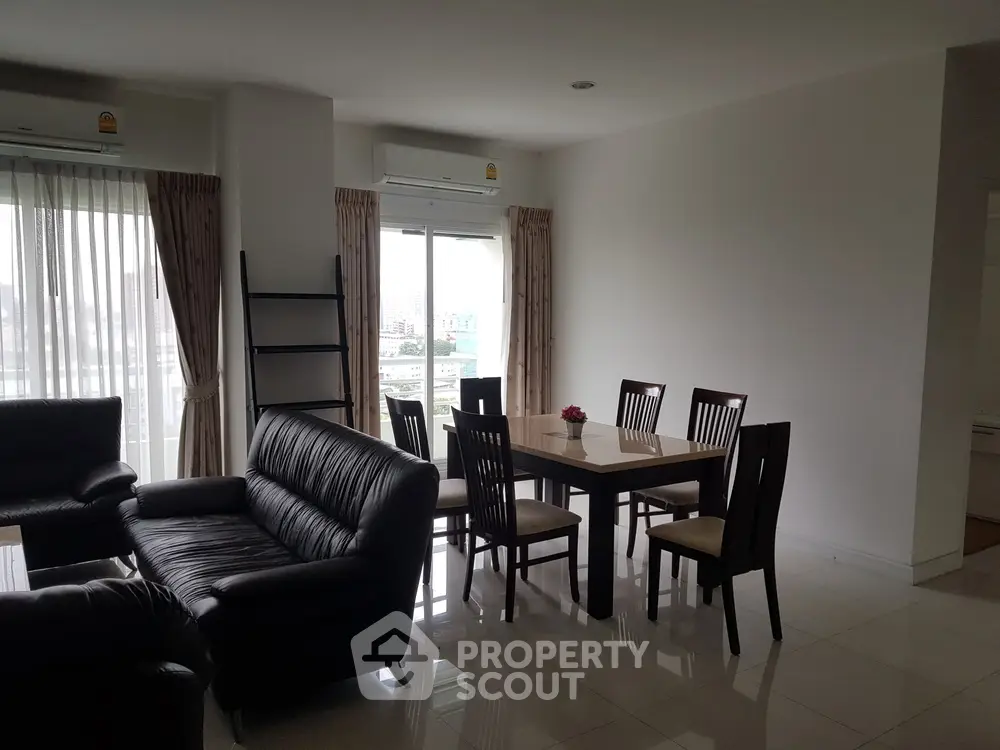 Spacious living room with modern furniture and large windows offering city views.
