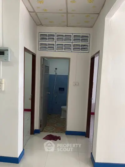 Simple bathroom entrance with white walls and blue accents in a residential property.