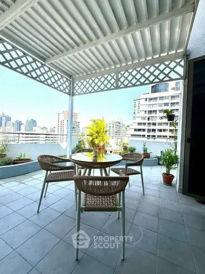 Spacious balcony with city view, featuring outdoor seating and lush greenery, perfect for relaxation and entertainment.