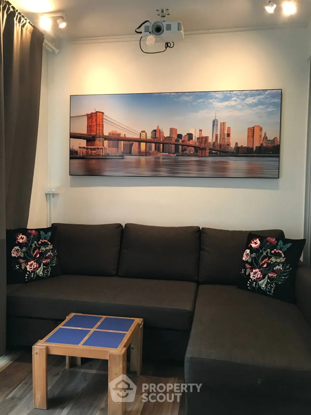Cozy living room with dark sofa, floral cushions, and cityscape artwork.