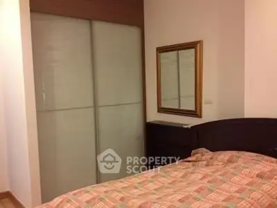 Cozy bedroom with mirrored wardrobe and stylish bedding in modern apartment.