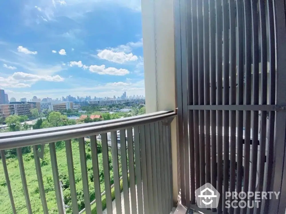 Stunning cityscape view from a modern balcony with lush greenery and clear blue skies.