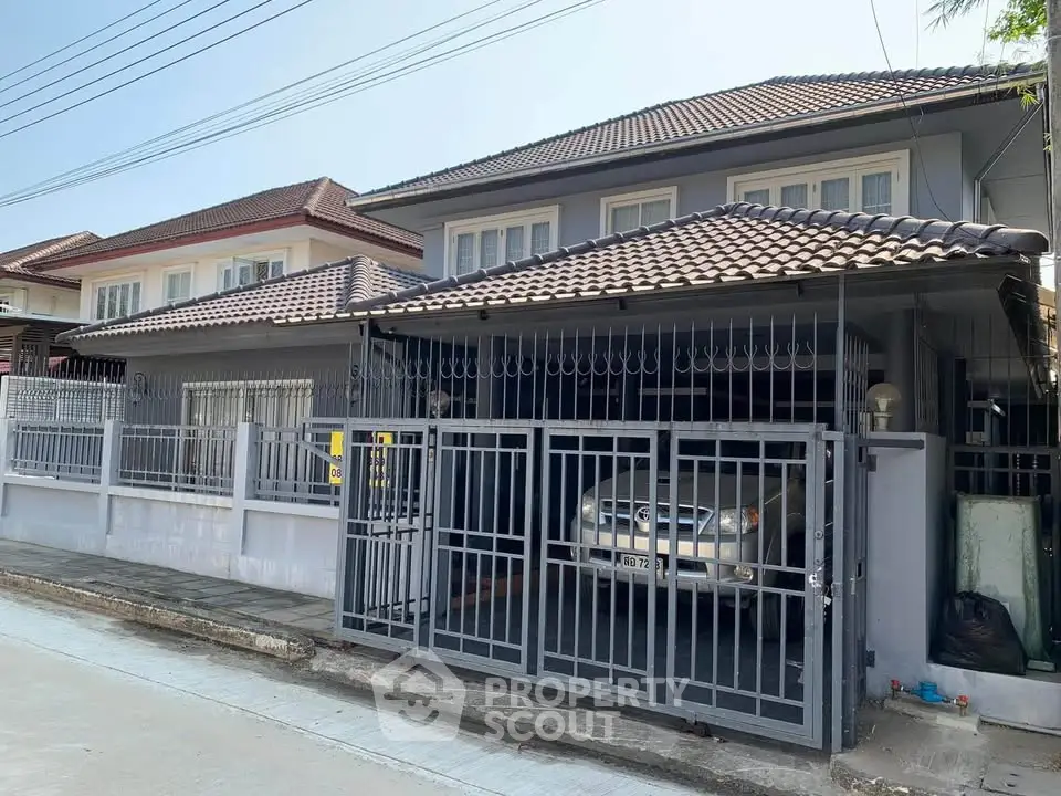 Charming suburban house with gated driveway and tiled roof, perfect for family living.