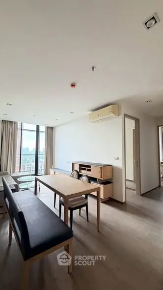 Spacious modern living room with city view, featuring sleek furniture and large windows.