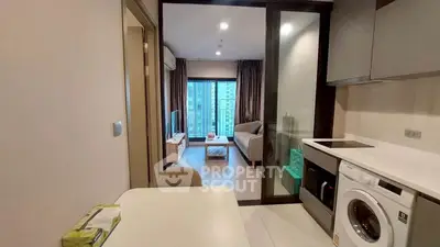 Modern apartment interior with open kitchen and cozy living room featuring a washing machine and city view.