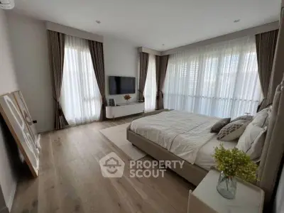 Spacious bedroom with modern decor and large windows for natural light.