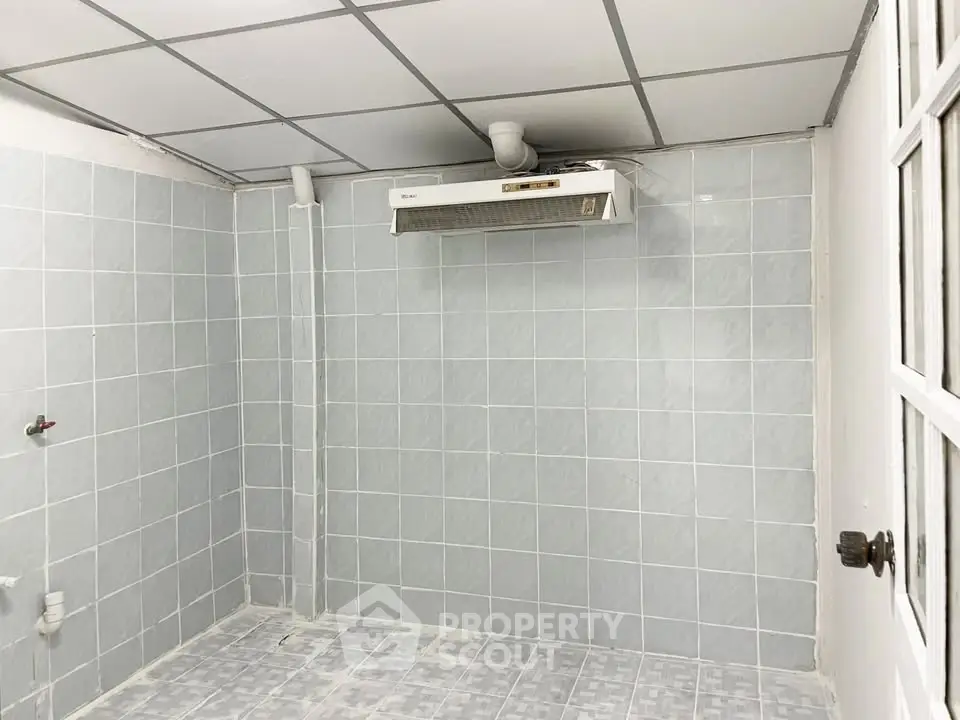 Empty tiled room with ceiling exhaust fan, ideal for kitchen setup.
