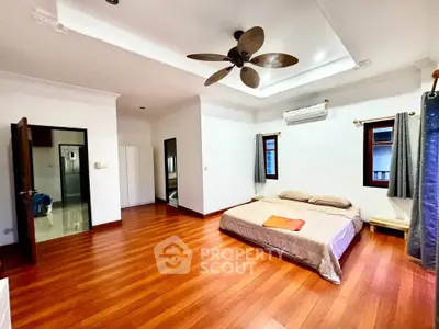 Spacious bedroom with wooden flooring and ceiling fan in modern home