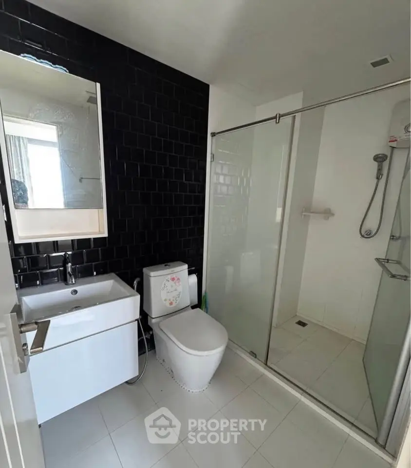 Modern bathroom with sleek black tile wall and glass shower enclosure