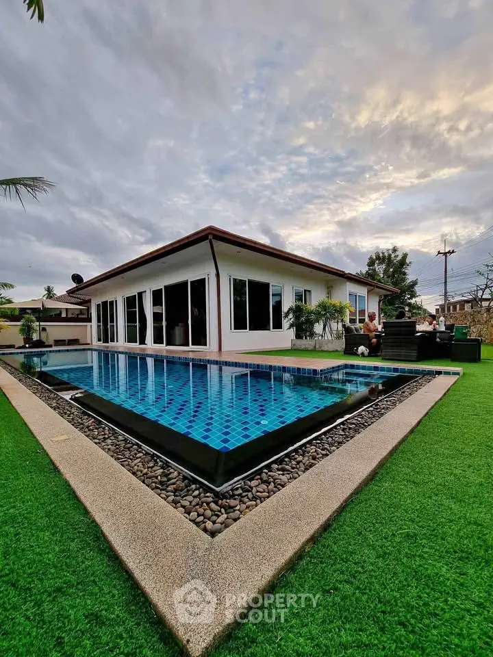 Stunning modern home with sleek pool and lush green lawn, perfect for luxury living.
