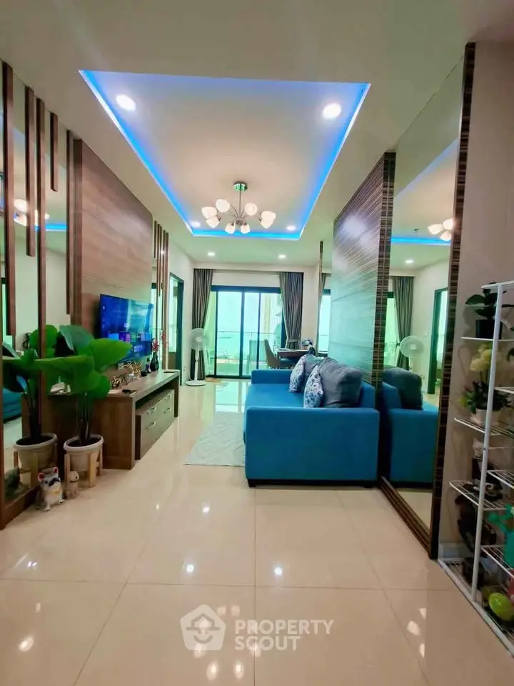 Spacious modern living room with blue sofa and elegant lighting, featuring a balcony view.