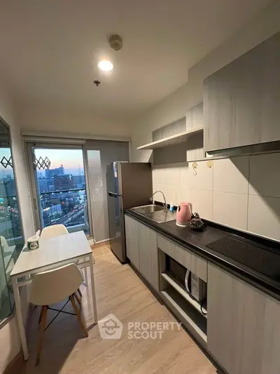 Modern kitchen with sleek cabinetry and city view from balcony, featuring dining area and stainless steel appliances.