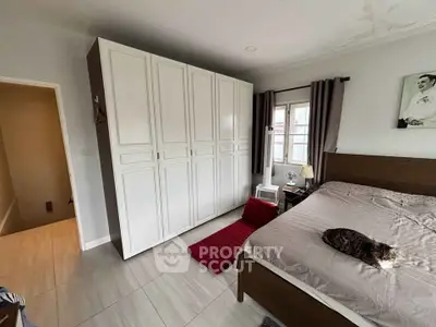 Cozy bedroom with large wardrobe and natural light, perfect for relaxation.