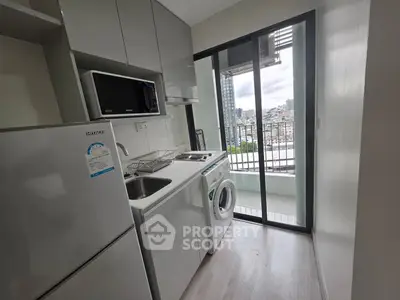 Modern kitchen with balcony view, featuring sleek appliances and ample natural light.