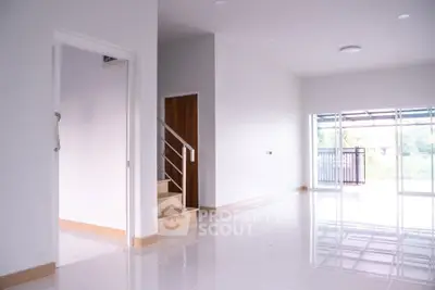 Spacious modern living room with large windows and staircase, perfect for natural light lovers.