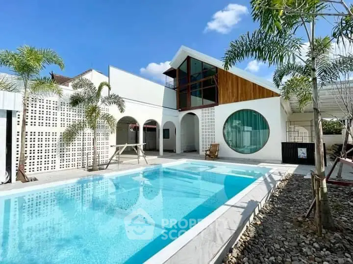 Stunning modern home with unique architecture and inviting pool under a clear blue sky.