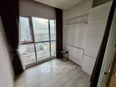 Spacious room with large window offering stunning city view in modern high-rise apartment.